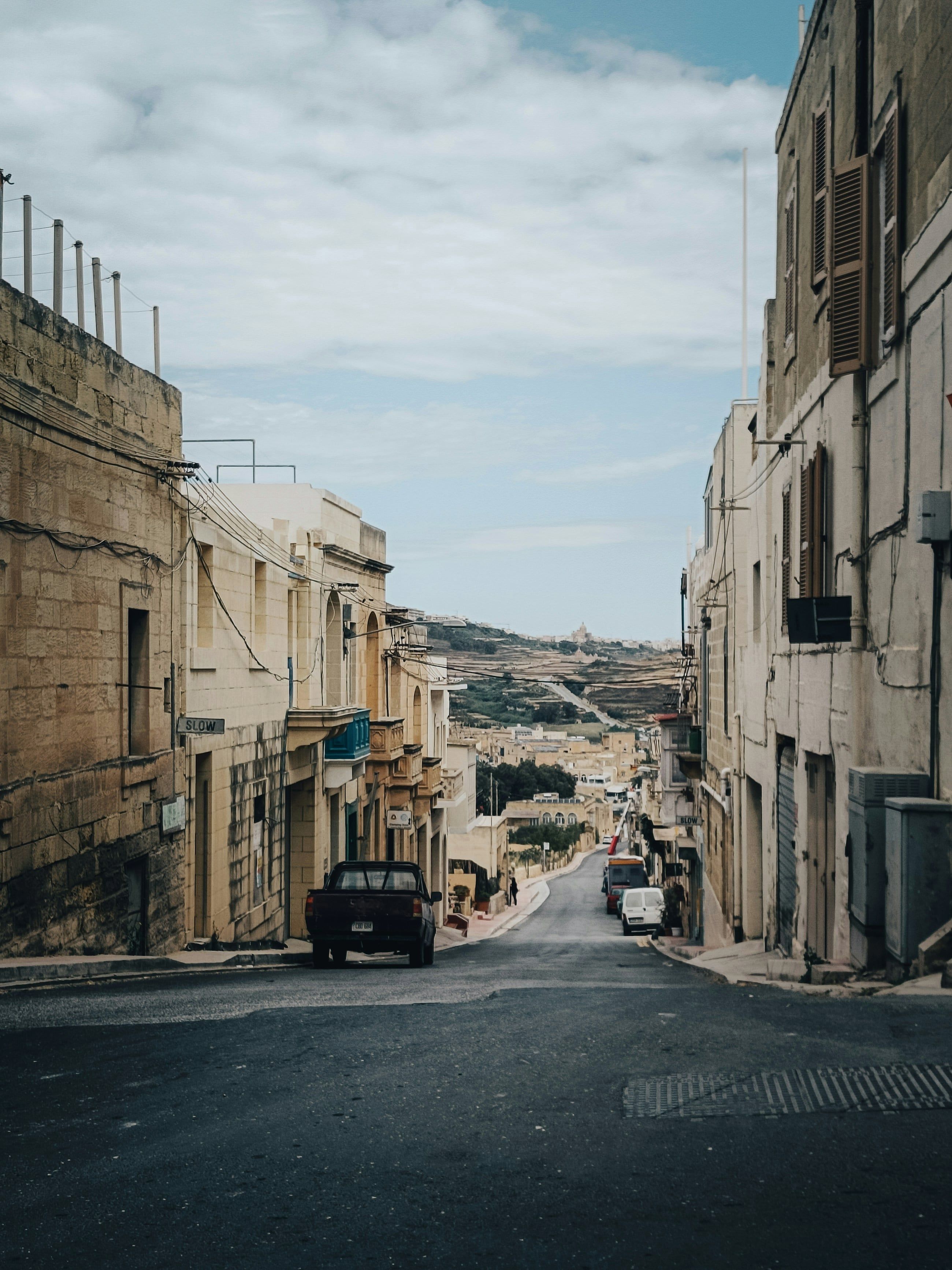 A quiet Gozo street falling away towards terraced fields