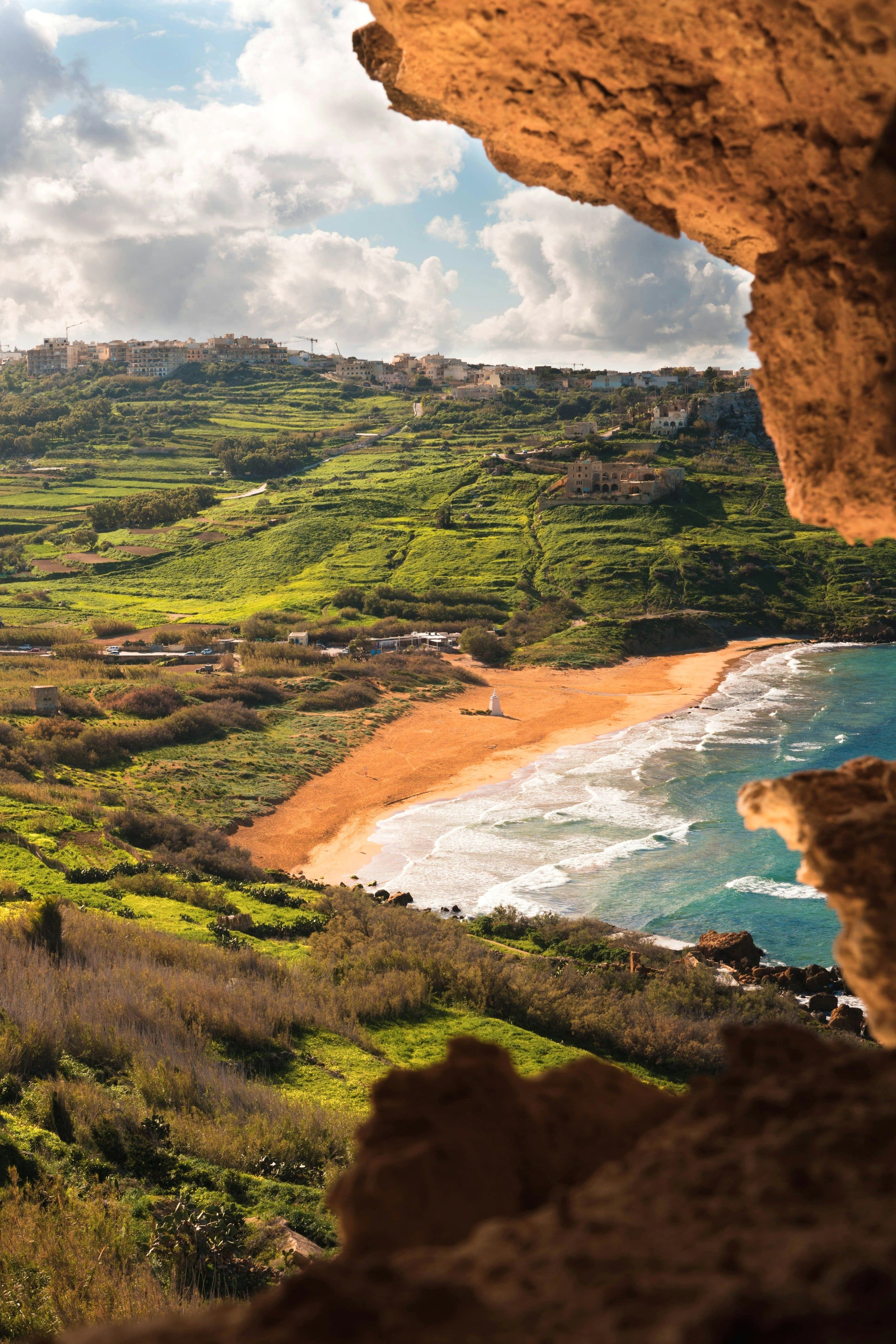Red sand at Ramla Bay on Gozo, framed by green terraces